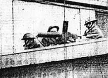 National Guard troops man machine gun emplacements on bulkhead building roofs.